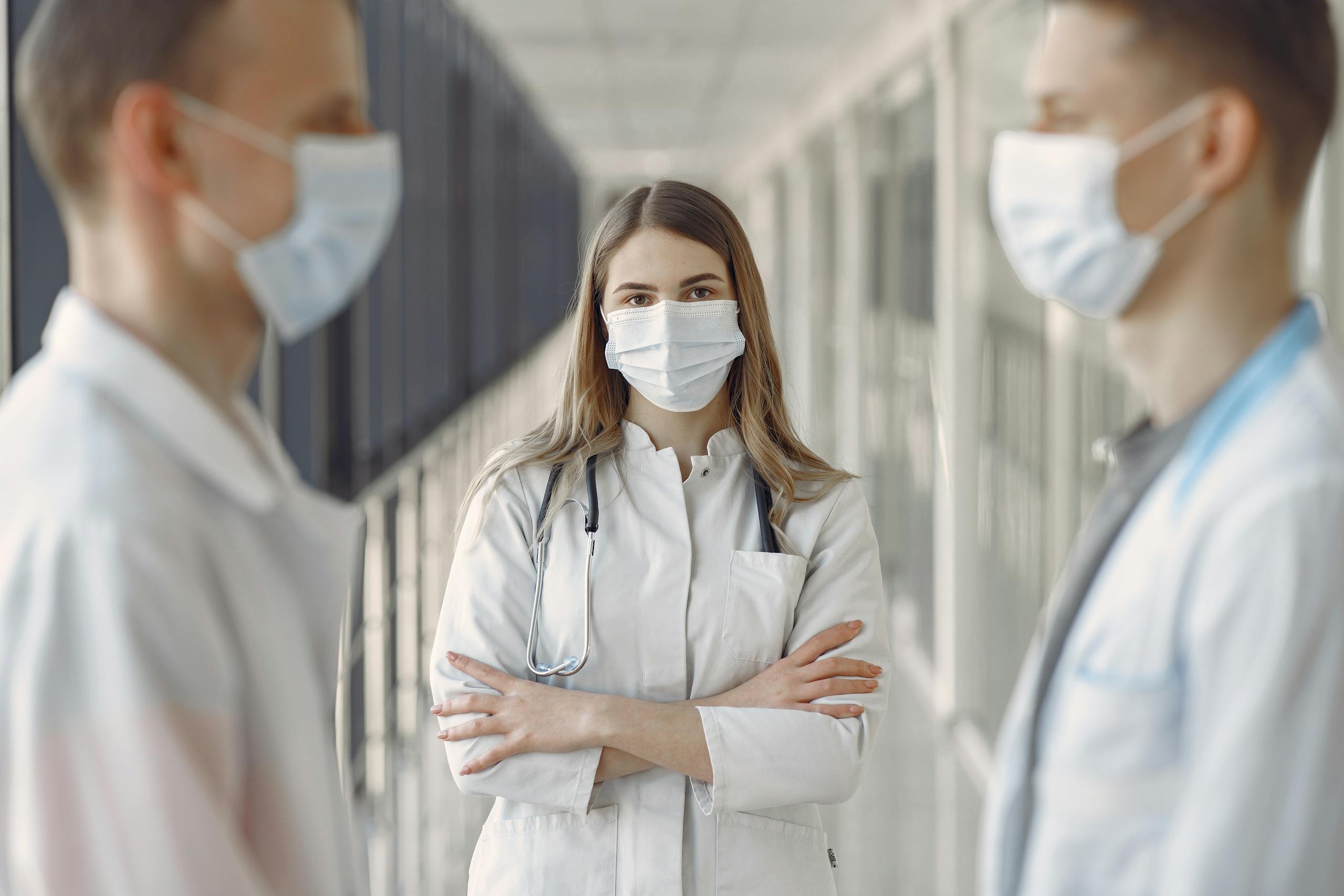 Medical professionals wearing face masks in a hospital hallway.